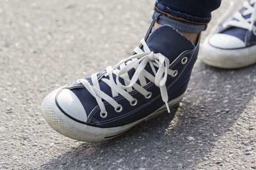 Close-up of female feet in fashionable sneakers are standing on the sidewalk