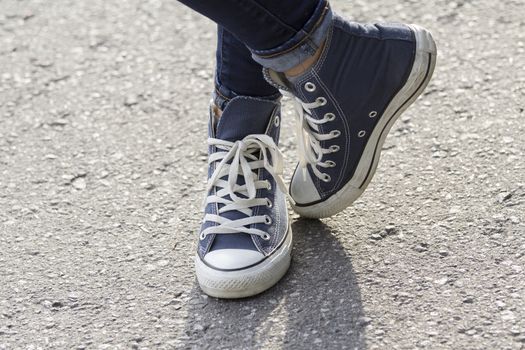 Close-up of female feet in fashionable sneakers are standing on the sidewalk