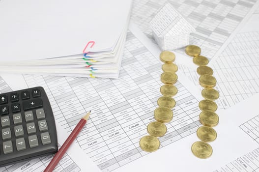 Pile of gold coins place as way to house on finance account have pencil with calculator and blur pile overload paperwork of report and receipt with colorful paperclip as background.