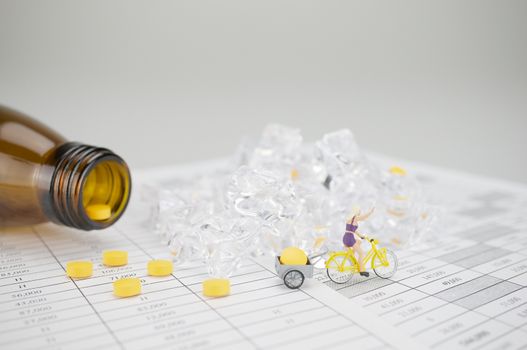 Woman is cycling and carry yellow pill on finance report have blur stack of ice and brown bottle as background.