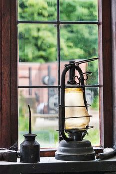 Antique kerosene lamp and oil can on the windowsill of an old artisan workshop.