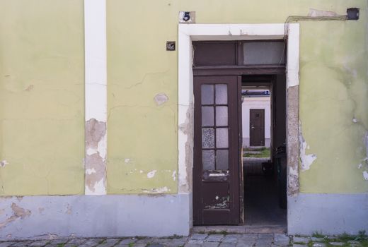 Facade of an old house with door from the street opened to a yard with next door. House number five. Mosonmagyarovar, Hungary.