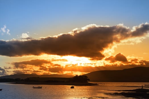 boats in a quiet bay with island near kenmare on the wild atlantic way ireland with an red sunset