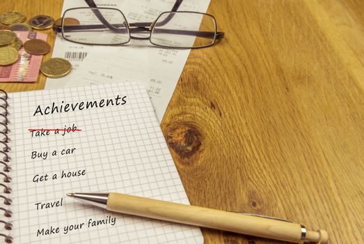 List of achievements written down in a spiral notebook, on a wooden desk