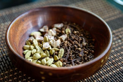 Cardamon, cloves and areca nuts in wooden bowl