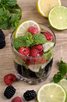 A glass of lemonade from the berries of blackberry and raspberry with lime and mint