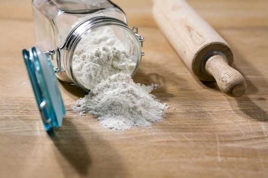 Flour in glass jar with rolling pin on a table