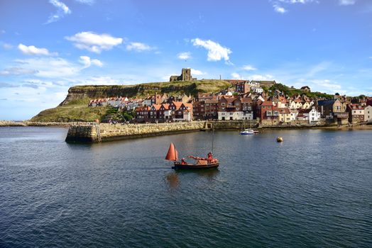 View of boat returning to Whitby Harbour and gothic church in background
