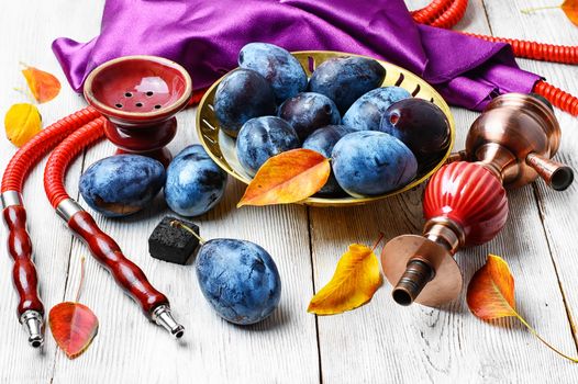 Still life with smoking hookah and the harvest of autumn plums