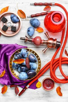 Still life with smoking hookah and the harvest of autumn plums