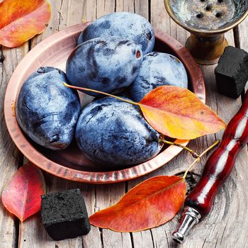 Still life with smoking hookah and the harvest of autumn plums