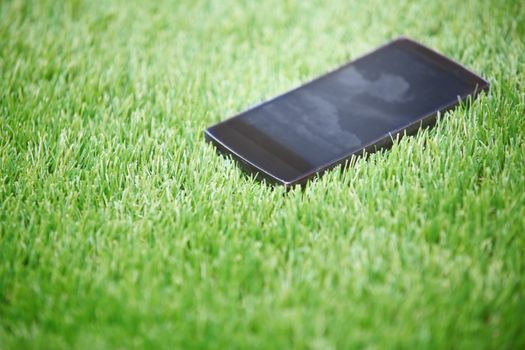 Smartphone lost in the grass. Horizontal photo