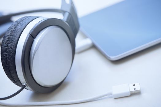 Headphones digital tablet and USB cable laying on a table