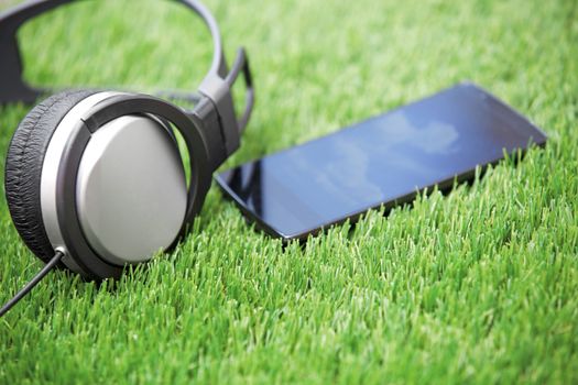 Headphones and smartphone laying on a grass