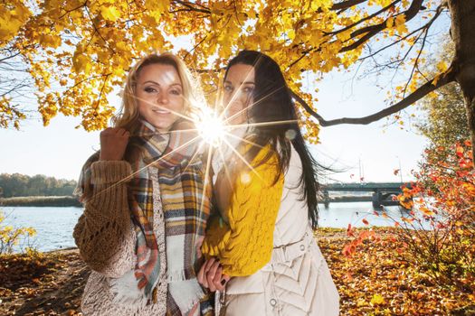 Two cheerful women in autumn park at sunny day