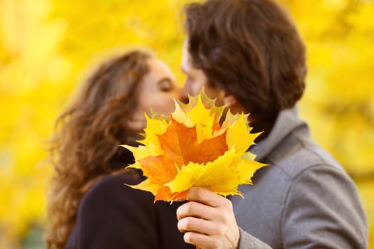 Happy couple kissing in autumn park with yellow trees