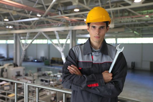 Young worker in hardhat with wrench at CNC factory