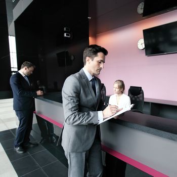 Business people filling forms at front desk