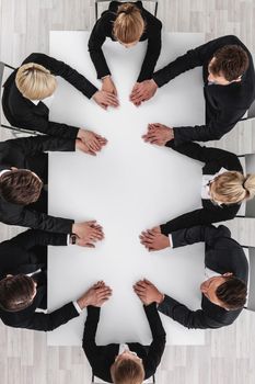 Diverse business people sitting around the table on a meeting and holding hands