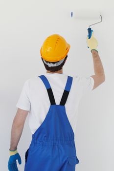 Young worker in hardhats painting the wall