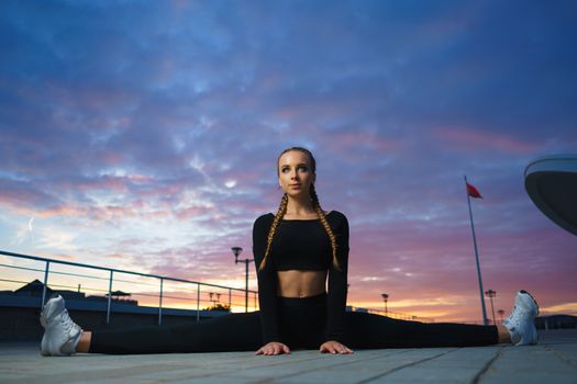 Concept: healthy lifestyle, sport. Attractive happy girl fitness trainer do outdoor workout at modern downtown urban area during sunset.