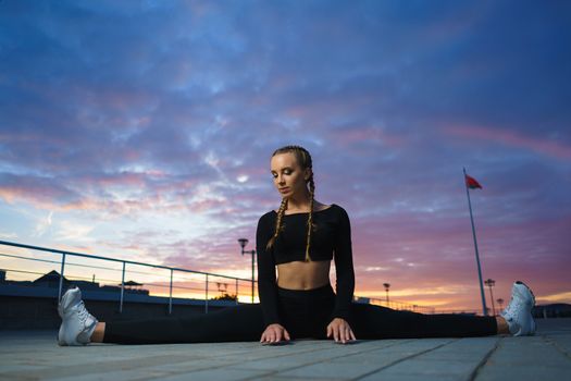 Concept: healthy lifestyle, sport. Attractive happy girl fitness trainer do outdoor workout at modern downtown urban area during sunset.