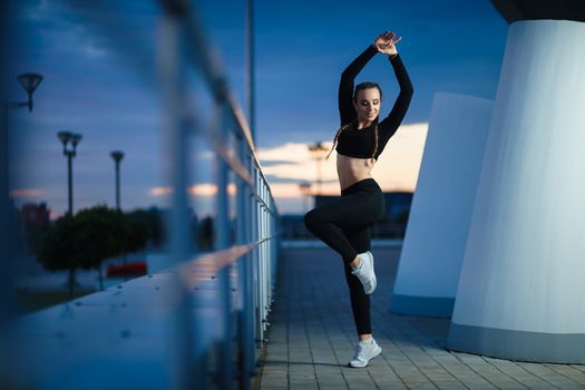 Concept: healthy lifestyle, sport. Attractive happy girl fitness trainer do outdoor workout at modern downtown urban area during sunset.