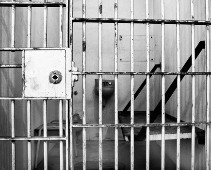 high contrast, high noise, gritty black and white image of an old prison cell