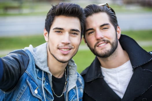 Two young men taking selfie while outdoors, point of view of the camera itself