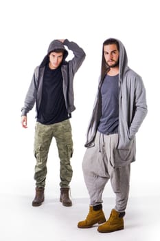 Two young men wearing military and sport clothes. Wearing hoods on heads. Studio shot.
