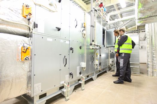 Workers in electrical switchgear room of CNC plant