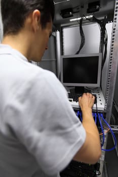 Young engeneer man in network server room connecting wires