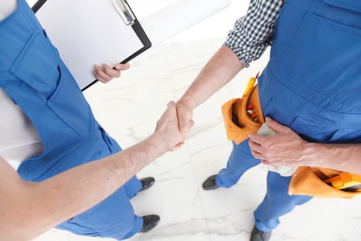 Two construction workers shaking hands, deal is finished concept