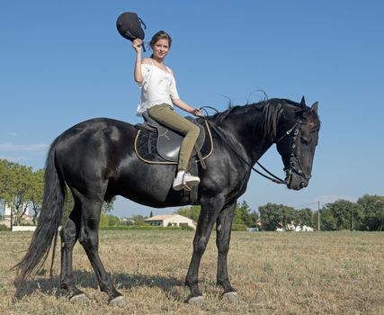 young girl riding a black stallion in a field