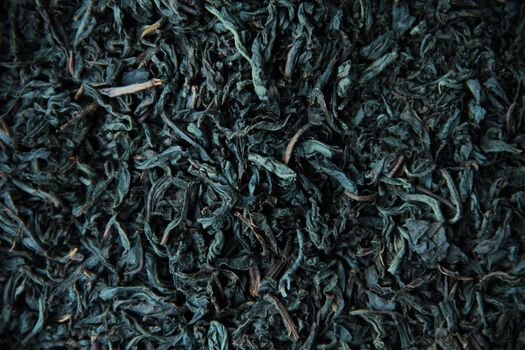 Black tea dry leaves close up background