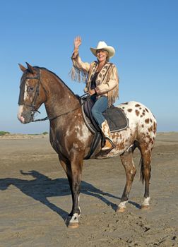 cowgirl on appaloosa horse on the beach