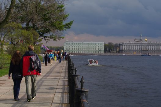 ST. PETERSBURG, RUSSIA, MAI 10, 2014: a few people walking on a cloudy promenade along the Newa river during late spring afternoon.
