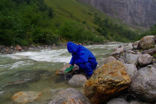 a man gold panning in a river with a sluice box