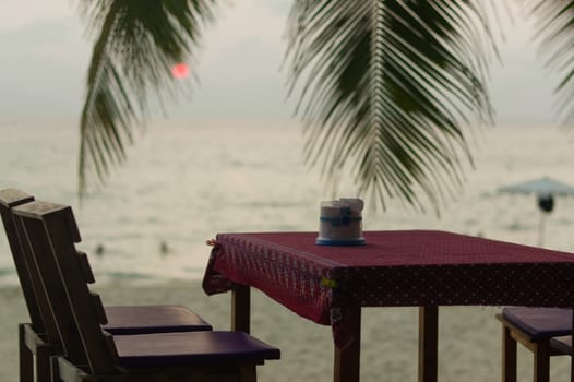 romantic outdoor restaurant table and chairs at the beach on sunset with plam leaves with seaview on a Maldives island