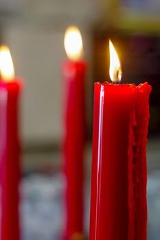 many prayer red burning long candles in budist temple