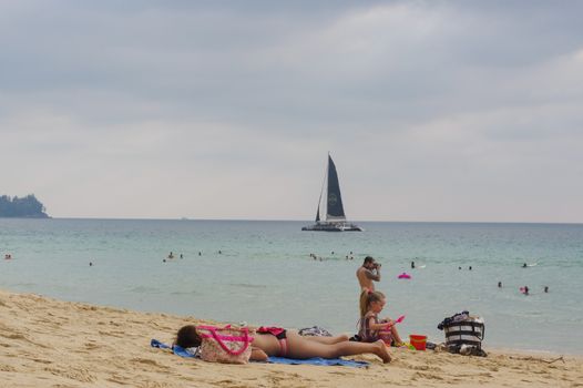 family enjoy sunbathe on white sand beach on Phuket island in Thailand