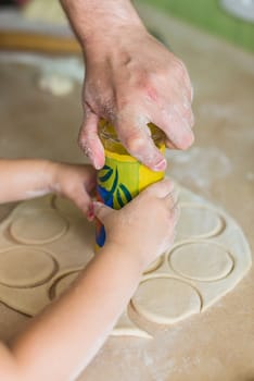 Children and dad cook hands the circles of dough