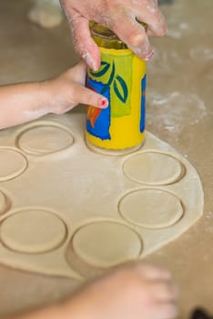 Children and dad cook hands the circles of dough
