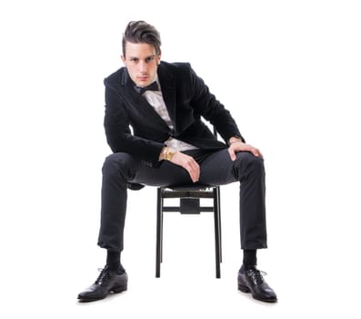 Young businessman confidently posing and looking to a side, wearing suit isolated in white background
