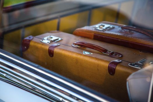 Two retro suitcase in retro car. Suitcases in the trunk of a car close-up of retro. Suitcases can be seen through the window of the car. The texture of carbon fiber on the trunk. Travel concept.