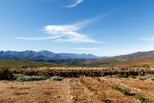 Beautiful brown and green landscape with clouds pointing to the Swartberg Pass mountains.