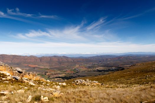 Farmland on a plato with mountains in the background looking over the beautiful Swartberg with clouds.