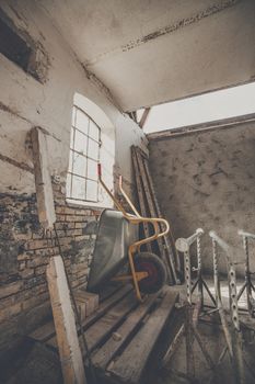 Wheelbarrow in a warn barn with sunlight coming through a window