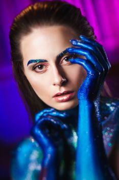 Portrait of an beautiful woman painted with purple cosmic colors and spangled. Body art project. Concept: fashion, makeup, extraordinary.