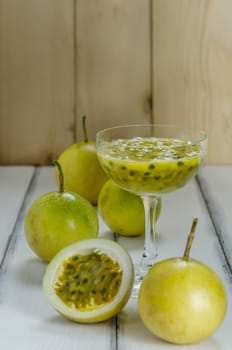 Fresh passion fruit juice in glass with passion fruits over wooden background , still life